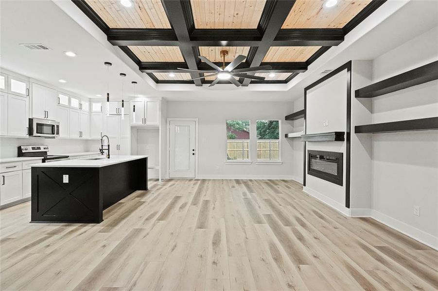 Kitchen with white cabinets, light hardwood / wood-style flooring, ceiling fan, range with electric stovetop, and an island with sink