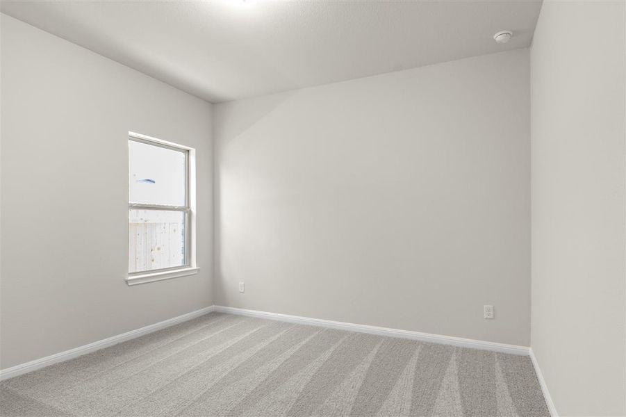 Empty room with light colored carpet and baseboards