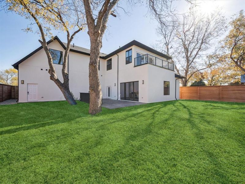 Back of house with a balcony, a yard, and a patio