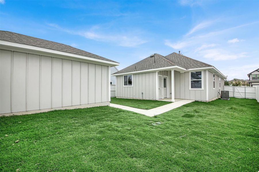 Rear view of house featuring board and batten siding, roof with shingles, and a fenced backyard