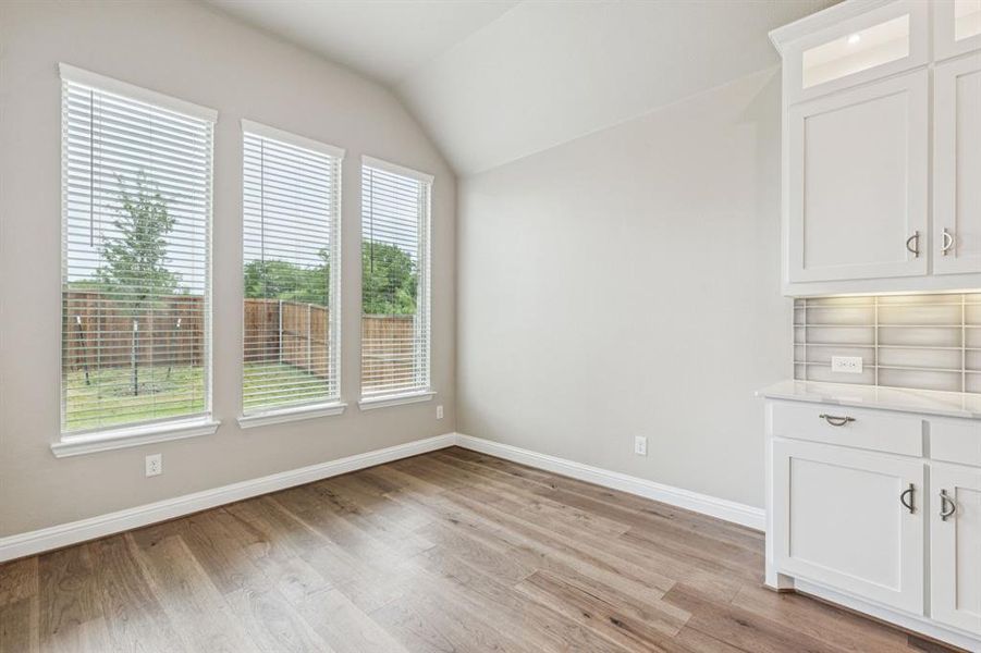 Unfurnished dining area featuring light wood finished floors and vaulted ceiling