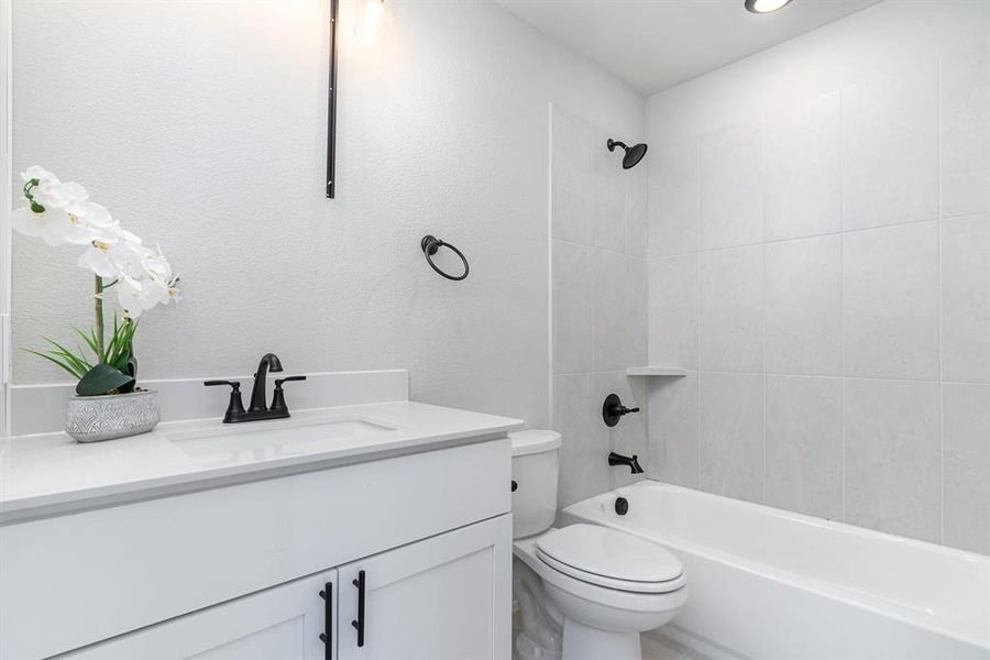 Full bathroom featuring toilet, vanity, and tiled shower / bath