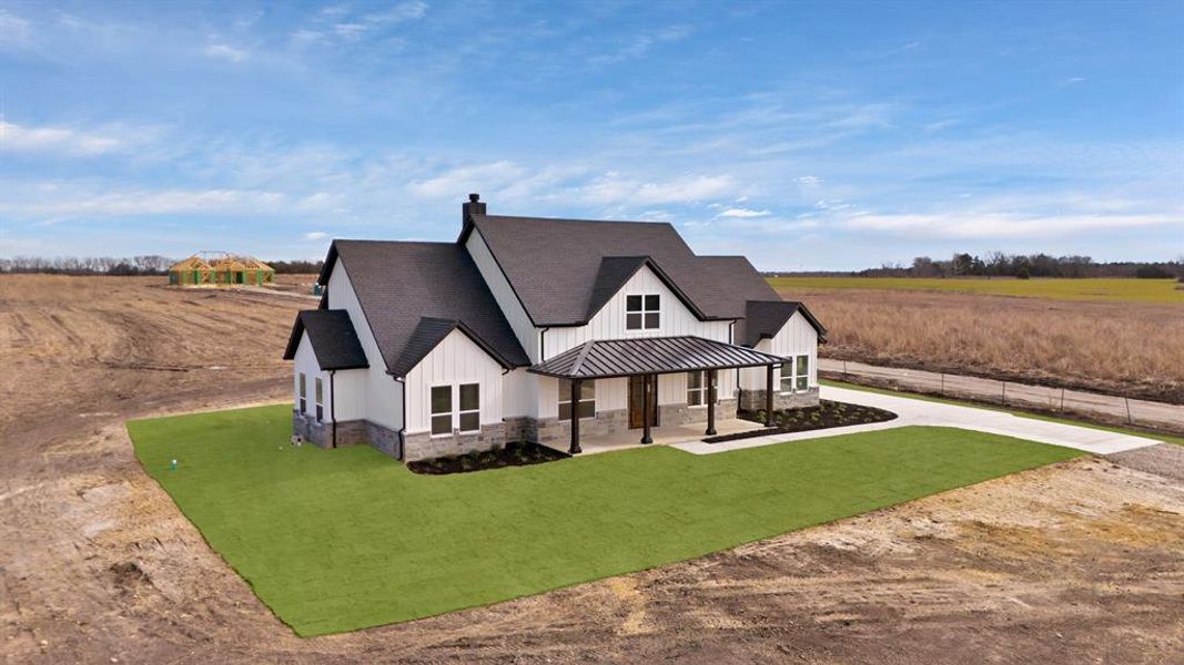 Modern farmhouse style home featuring a front yard and a rural view