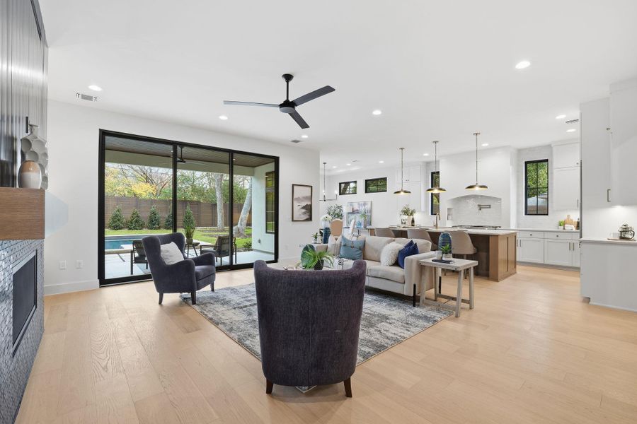 Living room with a fireplace, light wood finished floors, recessed lighting, and ceiling fan