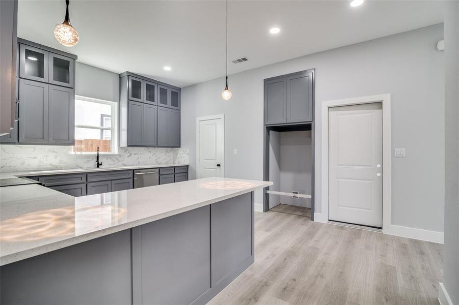 Kitchen featuring pendant lighting, sink, light wood-type flooring, and backsplash