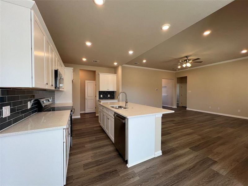 Kitchen with white cabinetry, sink, a kitchen island with sink, decorative backsplash, and appliances with stainless steel finishes