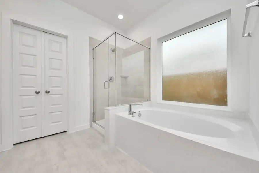 Indulge in a spa-like retreat within the confines of this primary bathroom. Delight in a spacious walk-in shower enveloped in stylish tile surround, unwind in a separate garden tub adorned with custom detailing.