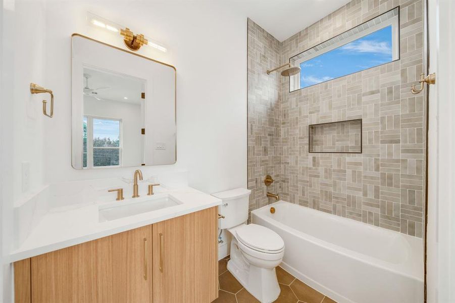 Bathroom featuring healthy amount of natural light, shower / bathtub combination, vanity, and dark tile patterned flooring Bathroom featuring healthy amount of natural light, shower / bathtub combination, vanity, and dark tile patterned flooring