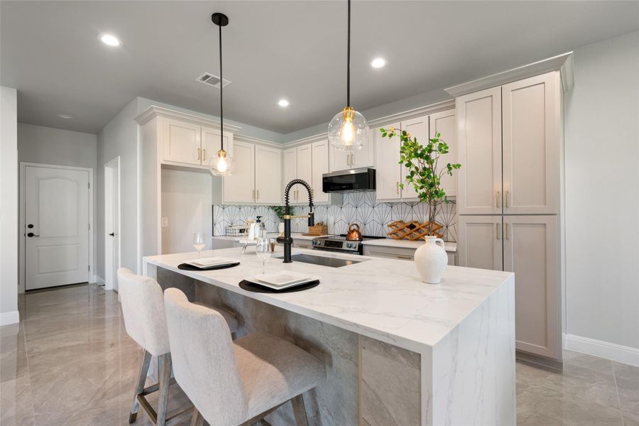 Kitchen featuring light stone counters, backsplash, hanging light fixtures, a breakfast bar, and light marble finish flooring