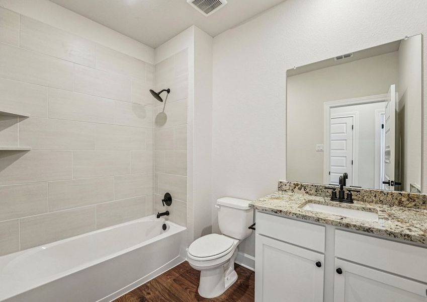 Secondary bathroom featuring a vanity with granite countertop and a tub/shower combination. Secondary bathroom featuring a vanity with granite countertop and a tub/shower combination.