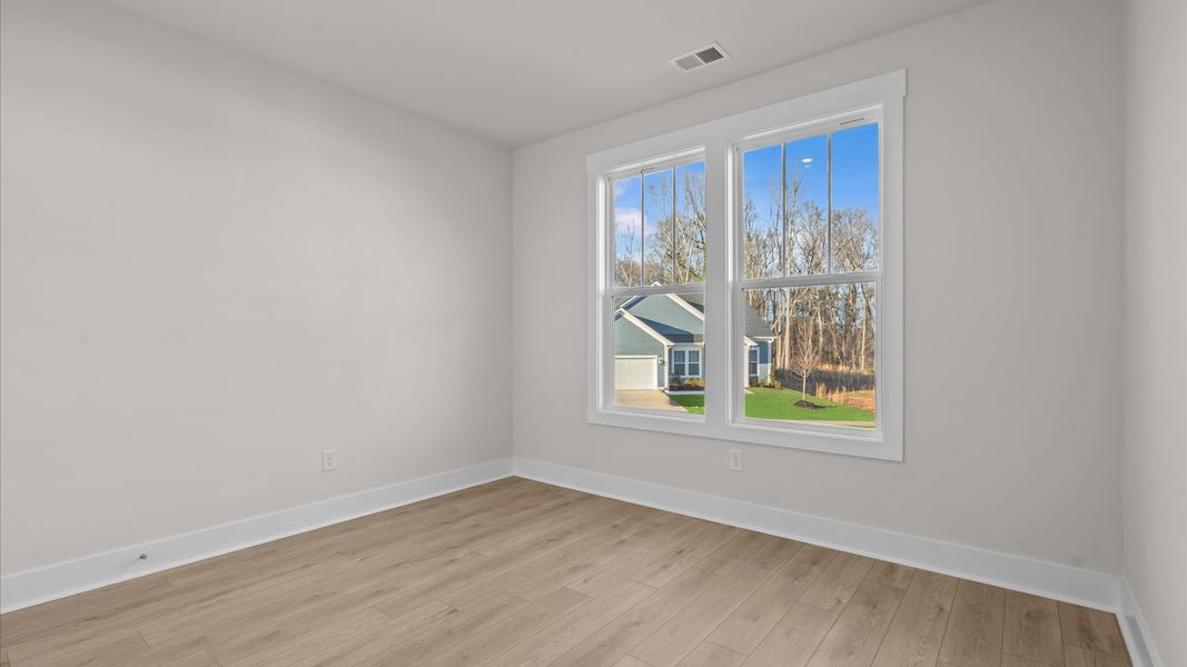Thoughtfully designed secondary bedrooms featuring hardwood flooring and tasteful detail