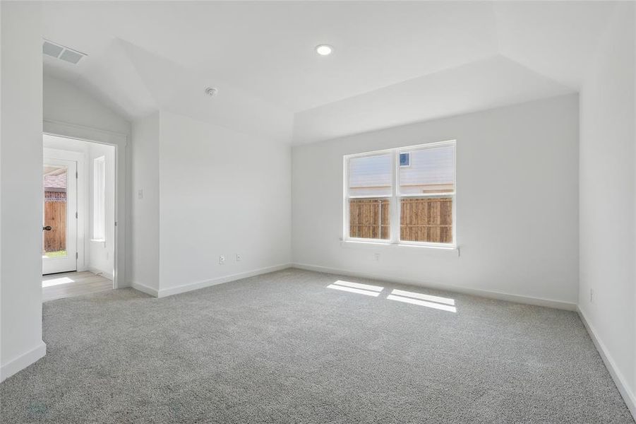 Spare room featuring light colored carpet and lofted ceiling