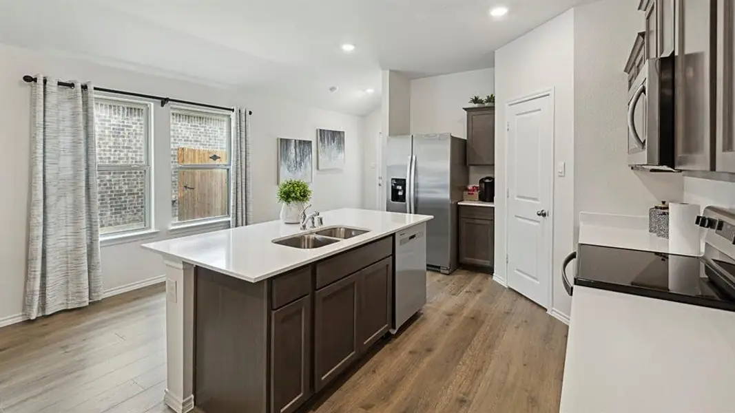 Kitchen with an island with sink, stainless steel appliances, dark wood finish cabinets, dark wood-type flooring, and lofted ceiling Kitchen with an island with sink, stainless steel appliances, dark wood finish cabinets, dark wood-type flooring, and lofted ceiling