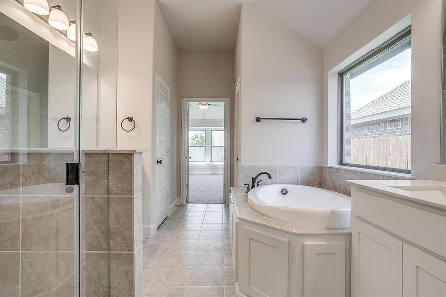 Bathroom with tile patterned flooring, lofted ceiling, independent shower and bath, and vanity