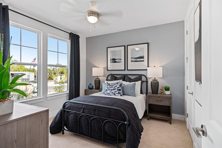 Bedroom featuring light carpet and ceiling fan. The photos shown are of a completed home with the same floor plan and may not reflect the exact finishes, features, or layout of the home currently under construction.
