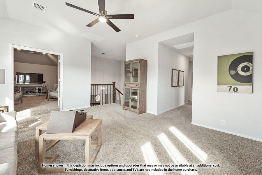 Upstairs loft area with carpet flooring, ceiling fan, staircase railing, and open view into adjacent room Upstairs loft area with carpet flooring, ceiling fan, staircase railing, and open view into adjacent room