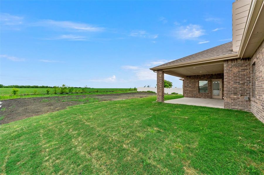 View of grassy yard featuring a patio area and a view of countryside