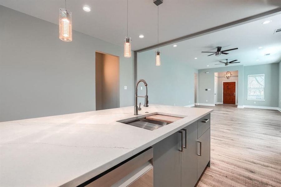 Kitchen with light wood-type flooring, ceiling fan, sink, decorative light fixtures, and gray cabinets