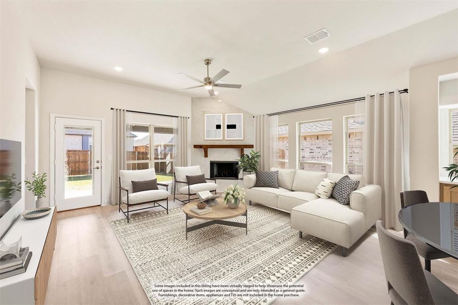 Bright living room with vaulted ceiling, fireplace, ceiling fan, and light wood floors Bright living room with vaulted ceiling, fireplace, ceiling fan, and light wood floors