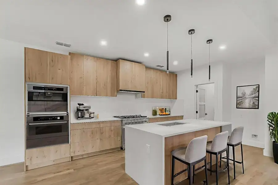 Kitchen with light brown cabinetry, light wood finished floors, modern cabinets, light countertops, and recessed lighting