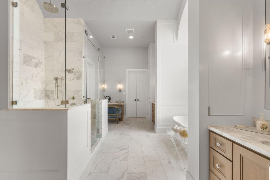 Stunning primary bath with large walk-in shower, soaking tub, two vanities with sinks and a third sit down vanity all with sconce lighting in addition to overhead lighting. Stunning primary bath with large walk-in shower, soaking tub, two vanities with sinks and a third sit down vanity all with sconce lighting in addition to overhead lighting.