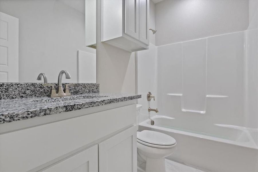 Full bathroom with tub / shower combination, toilet, vanity, and tile patterned floors