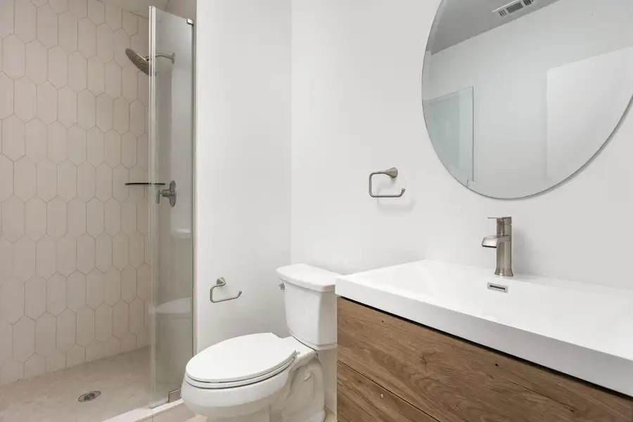 Bathroom featuring toilet, a shower stall, and vanity