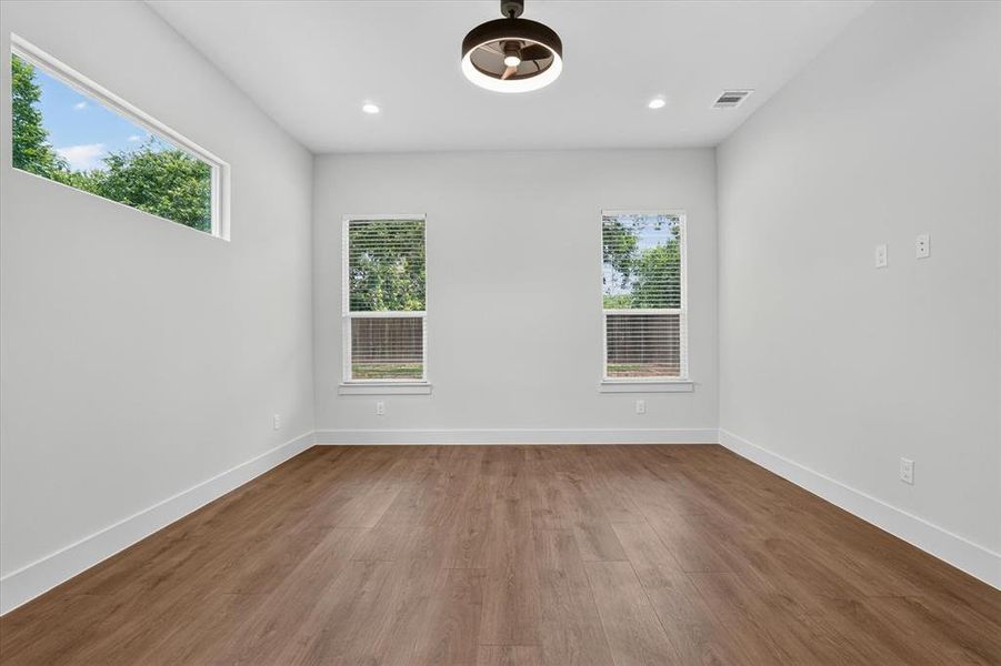 Spacious room featuring wood-finish flooring, white baseboards, and light neutral wall paint