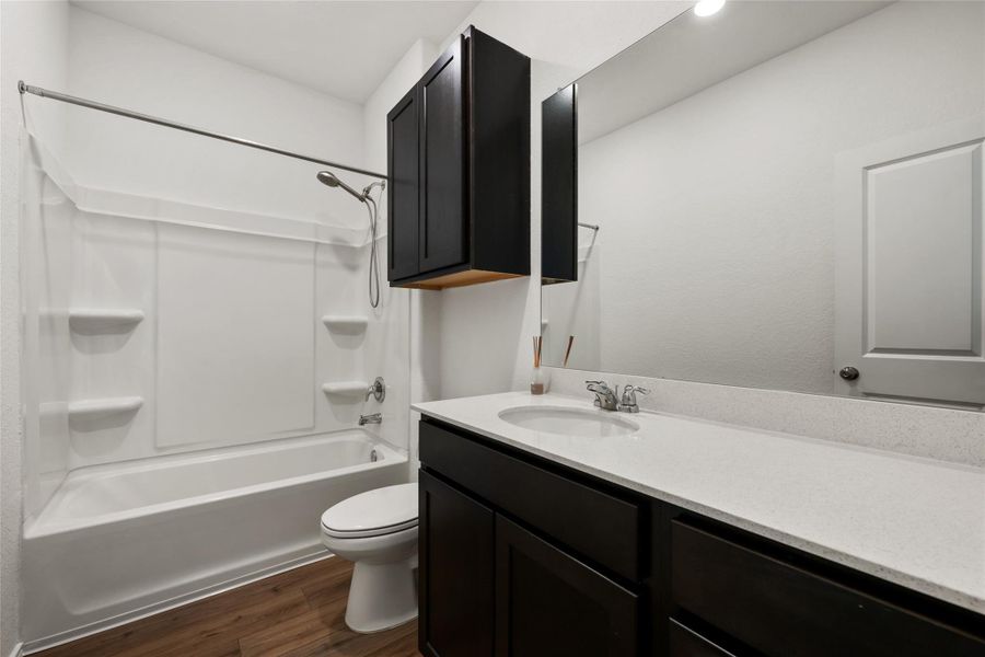 Full bathroom featuring wood finished floors, vanity, and washtub / shower combination Full bathroom featuring wood finished floors, vanity, and washtub / shower combination