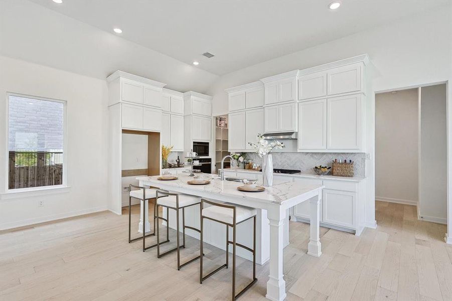 Kitchen featuring an island with sink, light hardwood / wood-style flooring, and white cabinetry