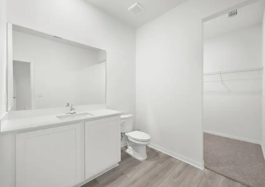 Master bath in the Braden - FL home in Fort Pierce, featuring a cultured marble vanity and view into the walk-in closet.