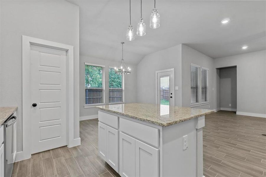 Kitchen featuring white cabinetry, light wood-type flooring, pendant lighting, and a kitchen island