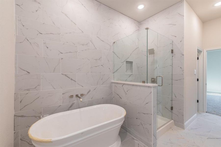 Bathroom featuring separate shower and tub and tile walls