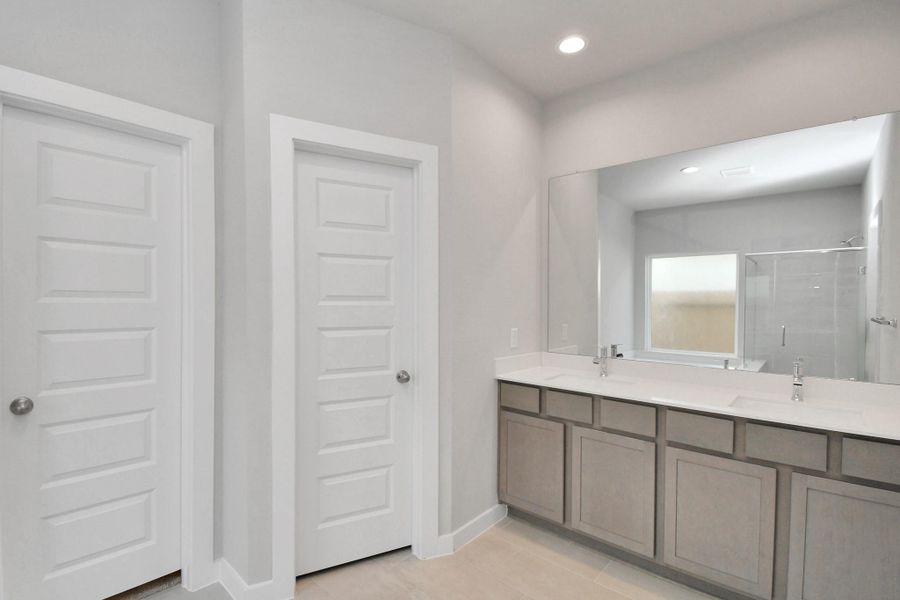 Elevate your daily routine at the elegant vanity, now equipped with double sinks, light countertops, modern hardware, and beautiful recessed lights. Sample photo of completed home with similar floor plan. Actual colors and selections may vary.