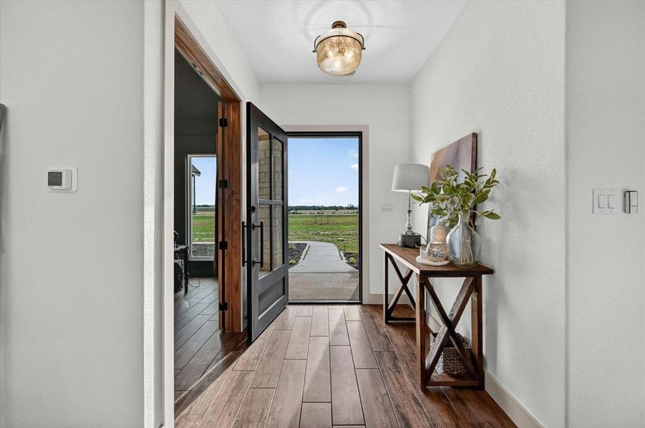Entryway featuring wood-finish flooring, a decorative glass flush-mount light fixture, and a black-framed glass-paneled door
