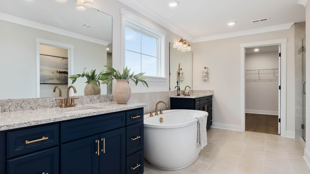 Stonefield home plan en suite primary bath with separate vanities, soaking tub and tile shower Stonefield home plan en suite primary bath with separate vanities, soaking tub and tile shower