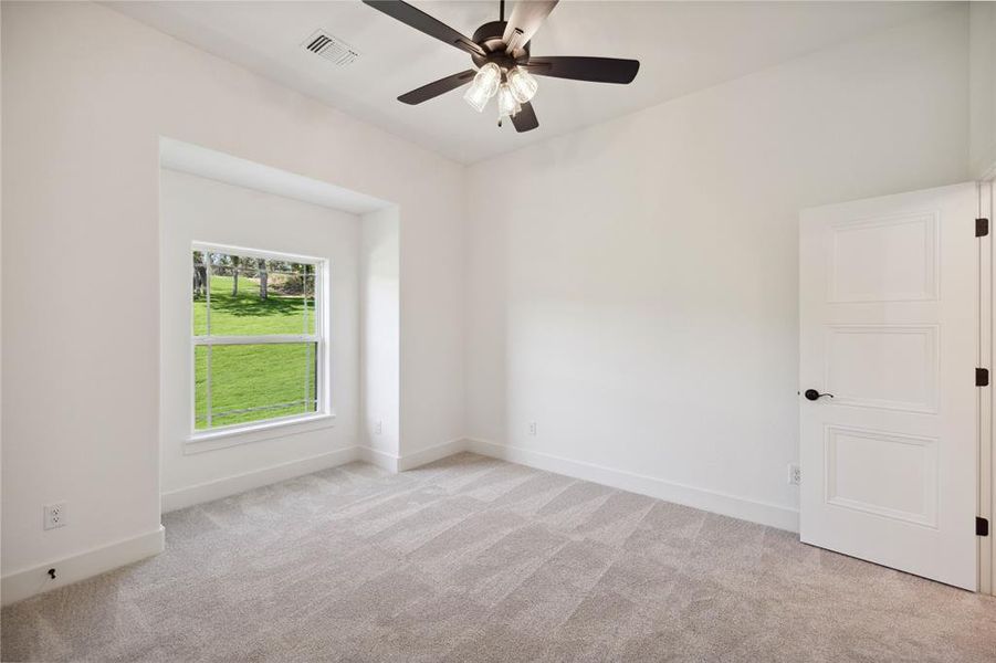 Carpeted empty room featuring ceiling fan