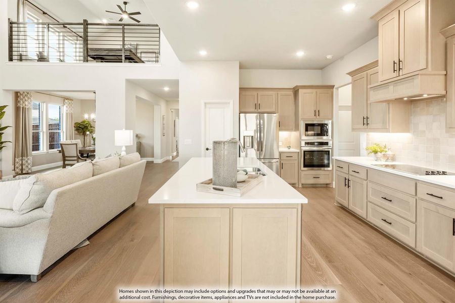 Open-concept kitchen with center island, beige cabinets, stainless appliances, and hardwood floors, open to living area with upper loft balcony.