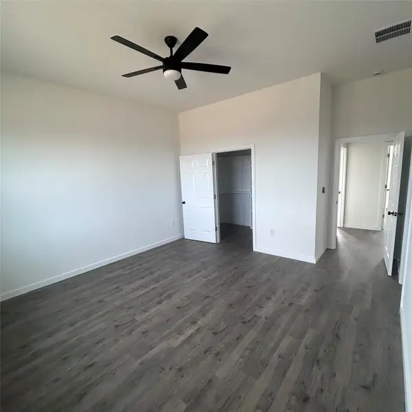 Unfurnished bedroom with a ceiling fan, dark wood finished floors, and a spacious closet Unfurnished bedroom with a ceiling fan, dark wood finished floors, and a spacious closet