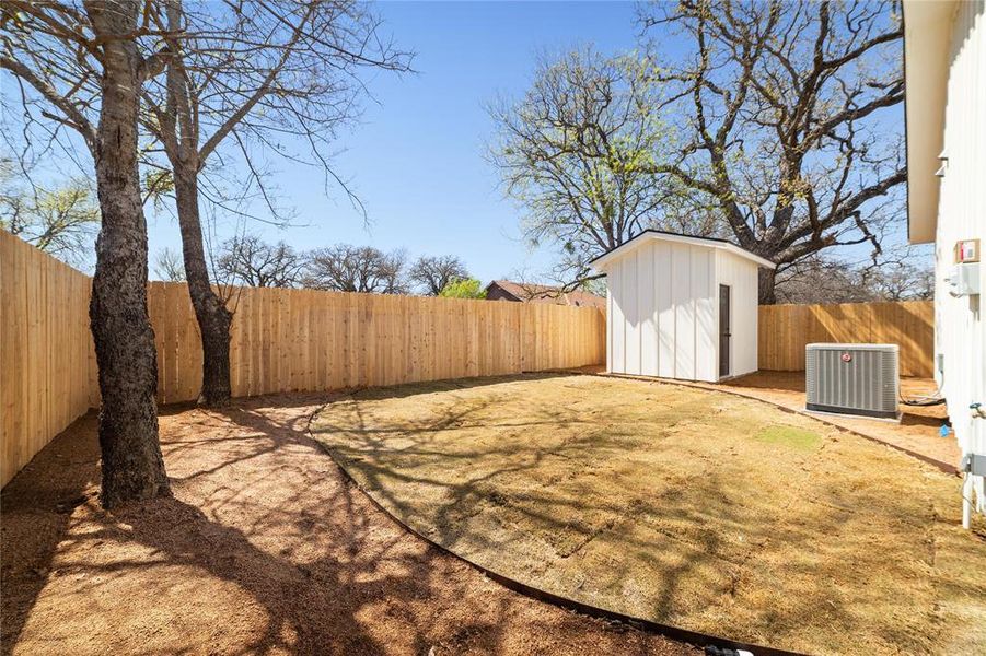 View of yard featuring an outbuilding, central AC unit, a fenced backyard, and a shed View of yard featuring an outbuilding, central AC unit, a fenced backyard, and a shed