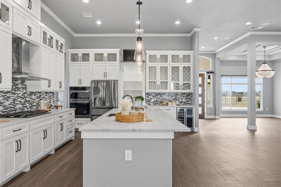 Kitchen featuring glass insert cabinets, light stone countertops, hanging light fixtures, and ornamental molding