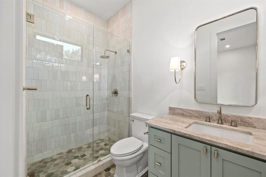 This bathroom features a spacious glass-enclosed shower with subway tile walls and a hexagonal tile floor