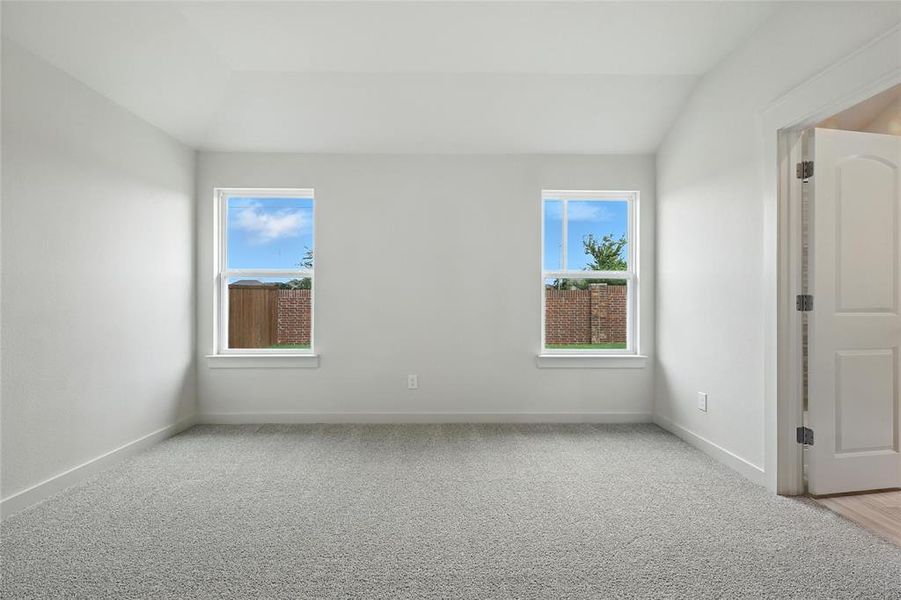 Spare room featuring vaulted ceiling and carpet floors Spare room featuring vaulted ceiling and carpet floors