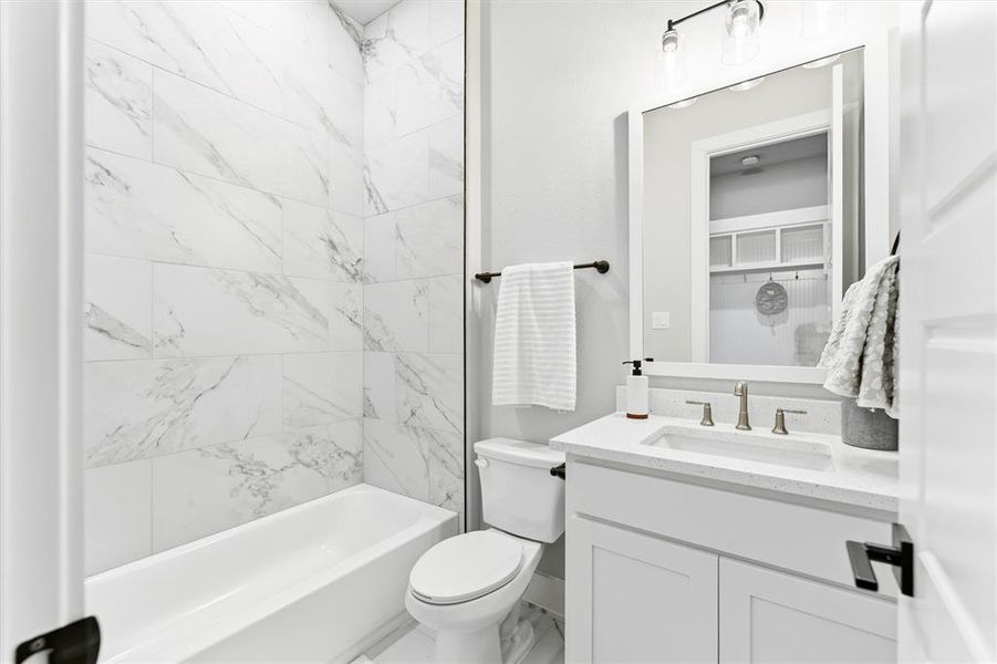Bathroom featuring vanity, tub / shower combination, and marble finish flooring