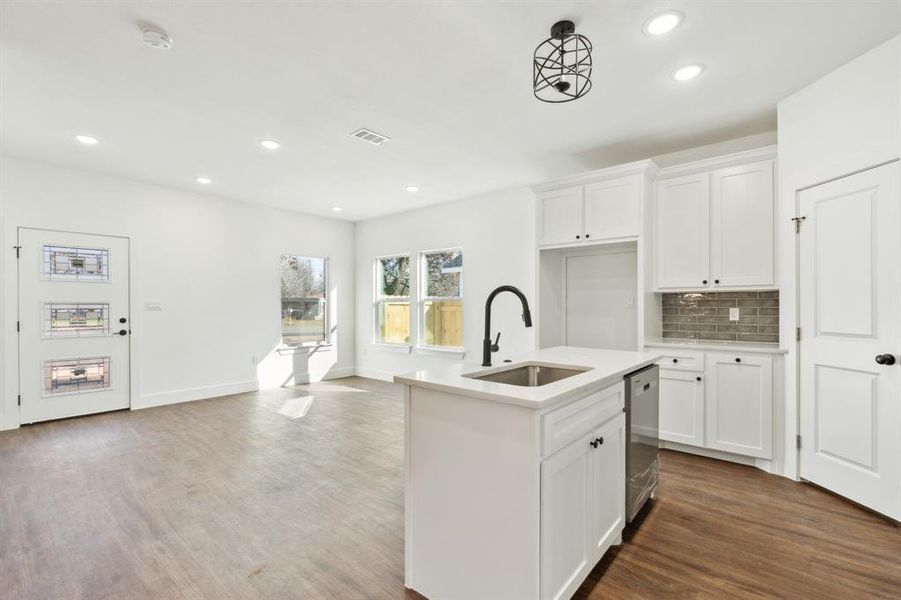 Kitchen featuring hardwood / wood-style flooring, white cabinetry, sink, and a center island with sink