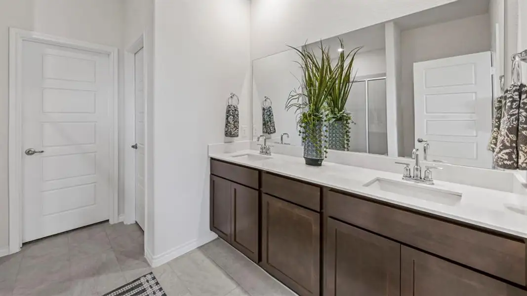 Bathroom featuring a double vanity with dark wood-finish cabinetry, white solid surface countertops, and two undermount sinks