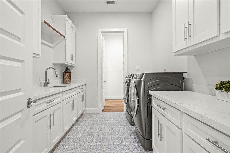 The Laundry Room is accessible from the hallway off the Garage and from the Primary Closet. The space boasts designer tile flooring, quartz countertops, an abundance of closed storage, hanging rack, and an undermount, stainless steel sink. The washer and dryer are not included but are negotiable. This Laundry Room perfectly marries both form and function!