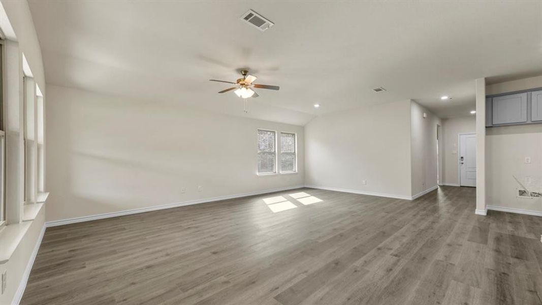 Spacious interior featuring wood-finish flooring, multiple windows, a ceiling fan, recessed lighting, and light gray cabinetry