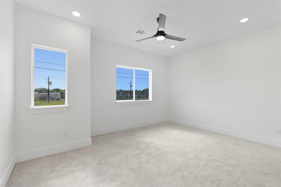 The spacious primary bedroom offers a calm and comfort, complete with carpeting and plenty of natural light. A modern ceiling fan and recessed lighting add both style and function, creating the perfect balance of coziness and modern style. This restful space is ideal for winding down after a long day.