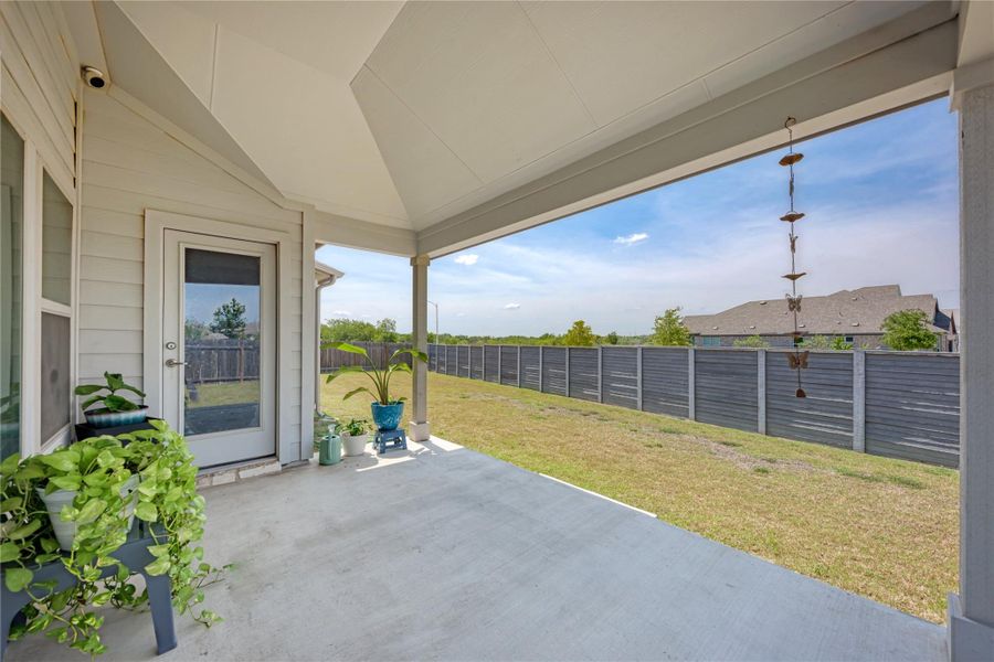 A spacious covered patio invites outdoor relaxation, overlooking a private fenced yard.